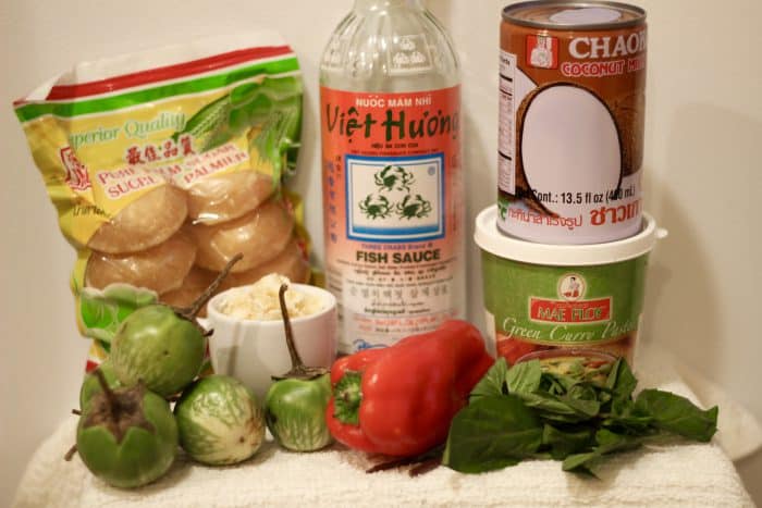 ingredients for thai green curry including fish sauce, palm sugar, mae ploy green curry paste, coconut milk, thai eggplant, red bell pepper, and lime leaf 