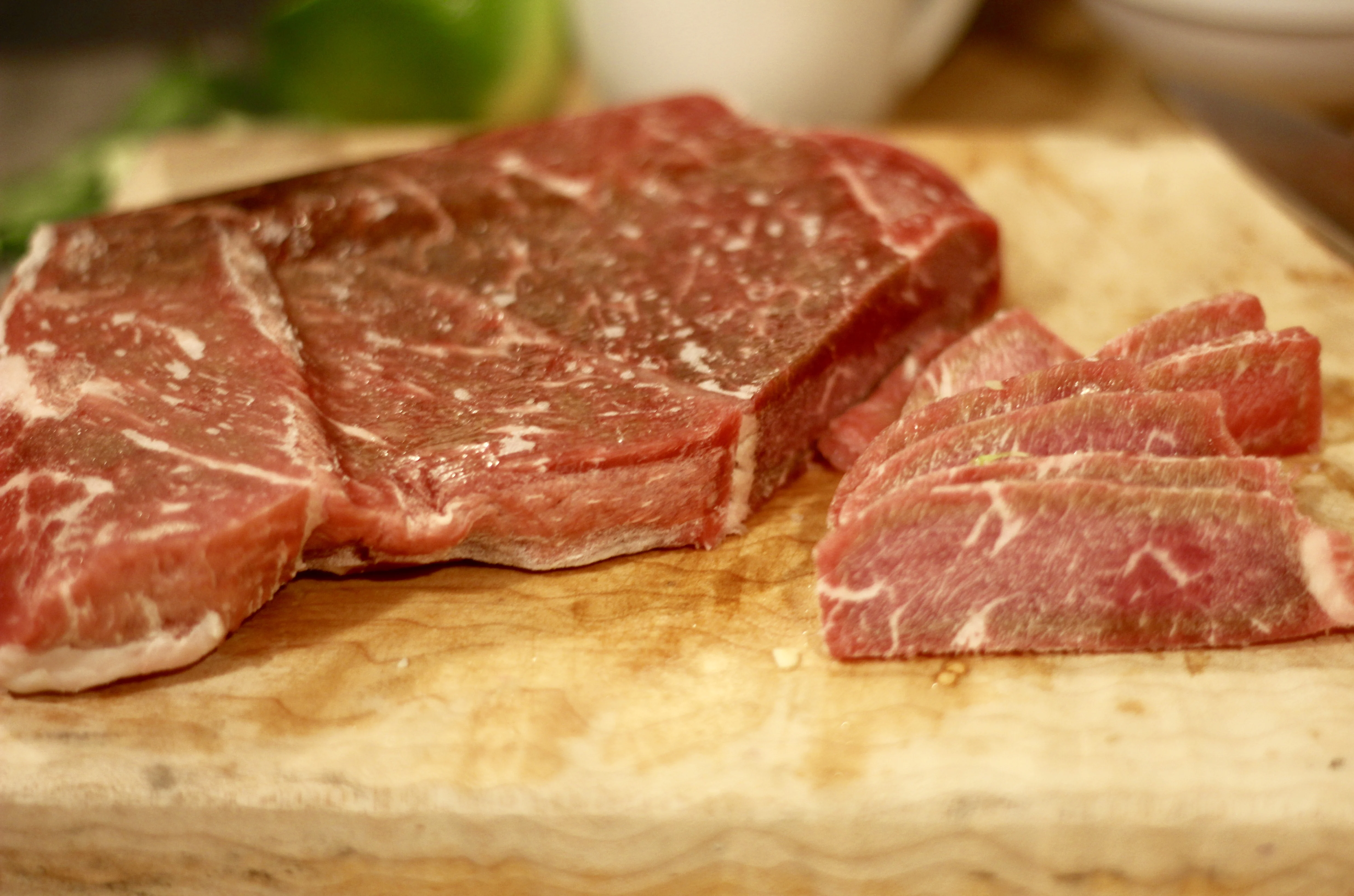 raw beef thinly sliced on a cutting board