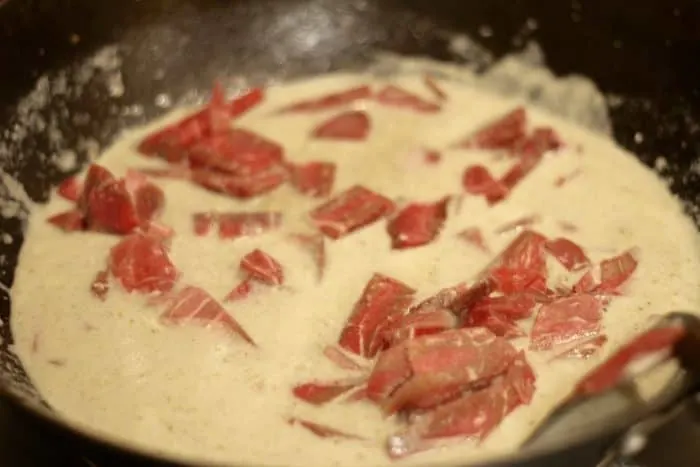 thin slices of raw beef cooking in green curry paste and coconut milk 