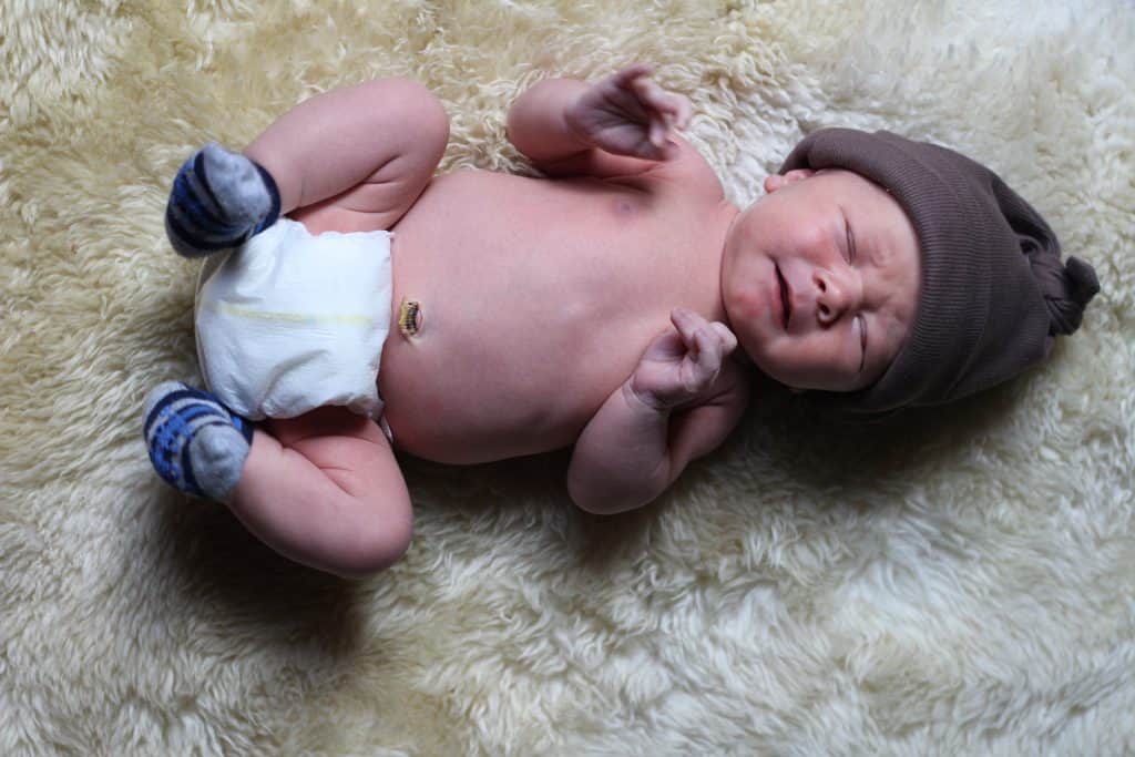 Newborn baby brother sleeping on a fur rug 