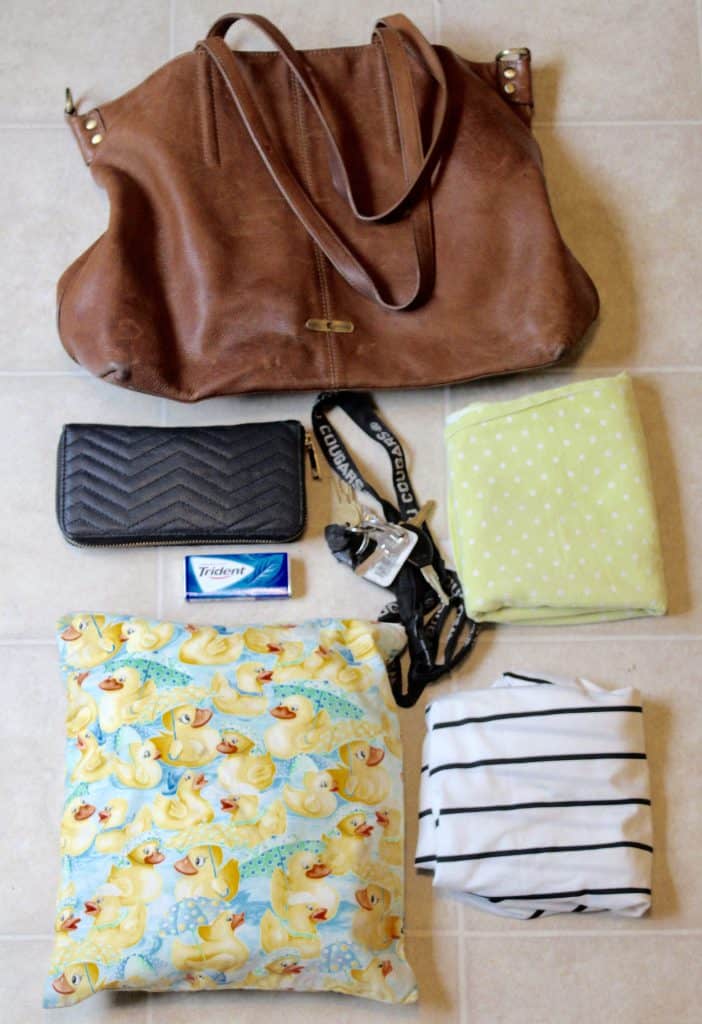 How I use my purse as a diaper bag. Filled minimally as my purse and diaper bag combined. Pictured are keys, wallet, swaddle, wet bag, and nursing cover. #blueandhazel #baby #newmom #momlife #diaperbag #kids