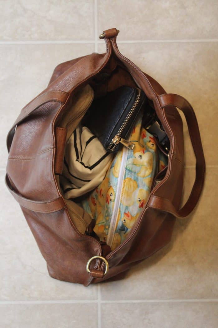Brown leather purse packed as a diaper bag with minimalist essentials like diapers, wipes, nursing cover, wallet, keys, and a few extras.