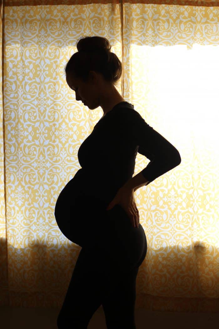  Pregnancy silhouette photo. Woman wearing black while she poses for a photo in natural light