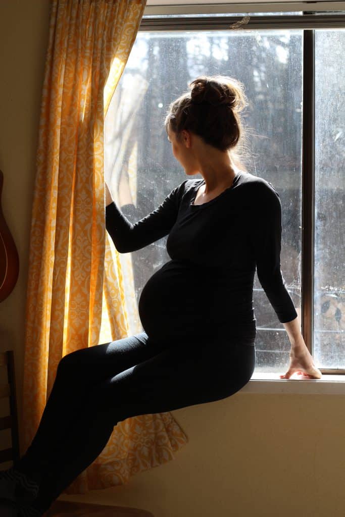 Pregnant woman posing in a window wearing all black for a pregnancy silhouette photo