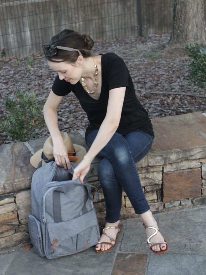 Mom of three kids reaching into her Laguna Tide diaper backpack while wearing a black nursing top. 