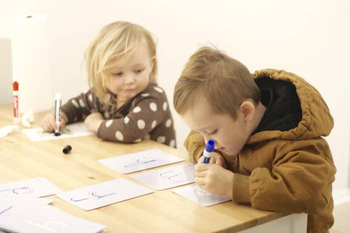 Preschoolers learning to write on wipeable Kumon letter flashcards, using an erasable marker