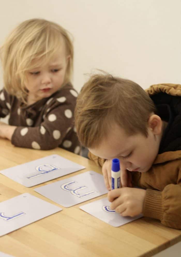 Reusable Kumon lowercase letter flashcards used by two preschoolers for learning to trace letters