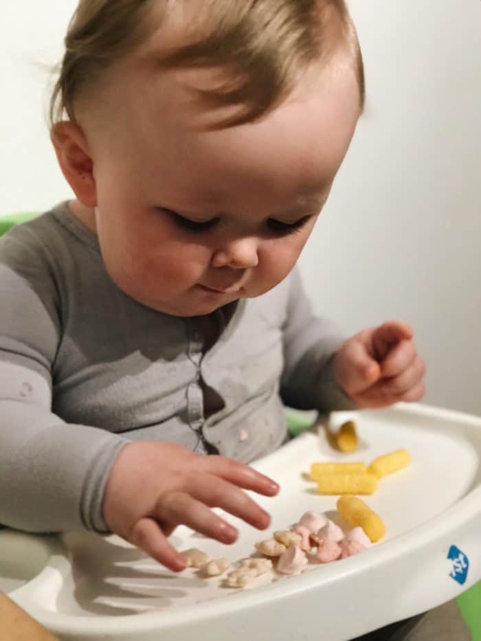 a baby in a highchair eating gerber puffs and gerber lil crunchies, some of his favorite baby led weaning foods 