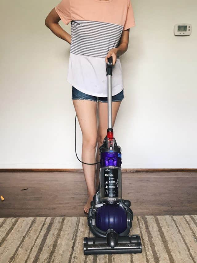 A woman vacuuming with a Dyson vacuum doing daily house cleaning