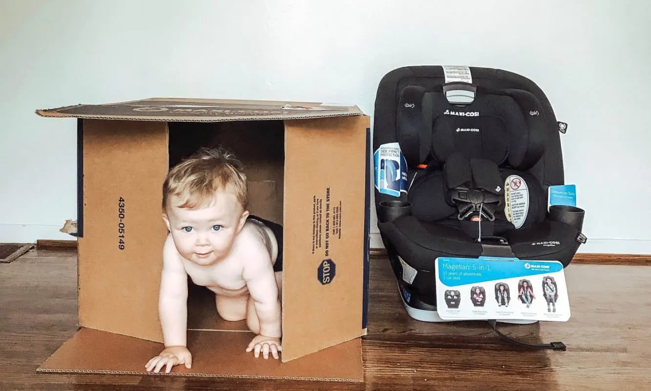 Baby peeking out of a box after unboxing a Maxi-Cosi Magellan Convertible Car Seat