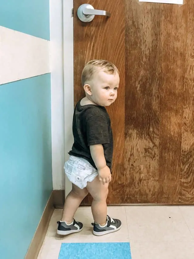 a toddler exploring the waiting room with blue walls before the doctor arrives.