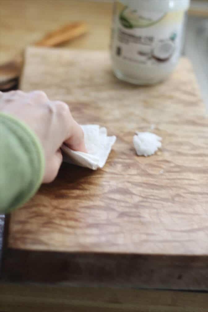 Rubbing coconut oil into a wooden cutting board to season.