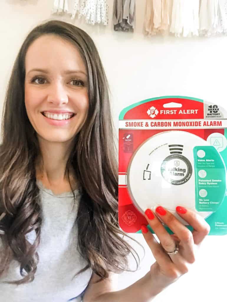 First Alert Smoke and Carbon Monoxide Alarm new in package held by a woman smiling. 