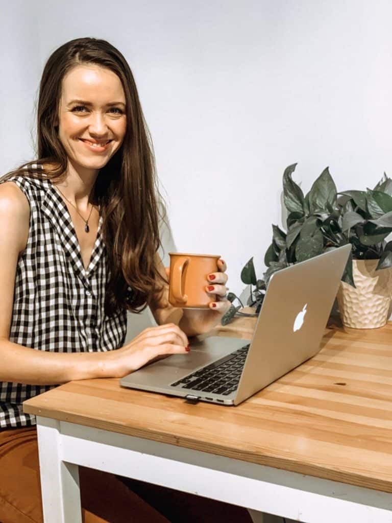 A mom working on her computer in a gingham shirt