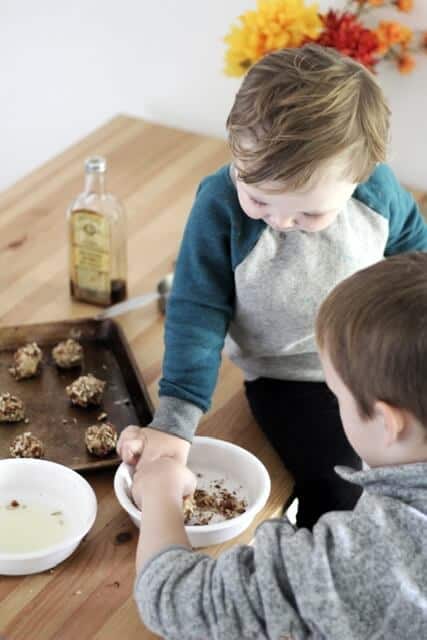 kids rolling thumbprint cookies in egg whites and chopped pecans