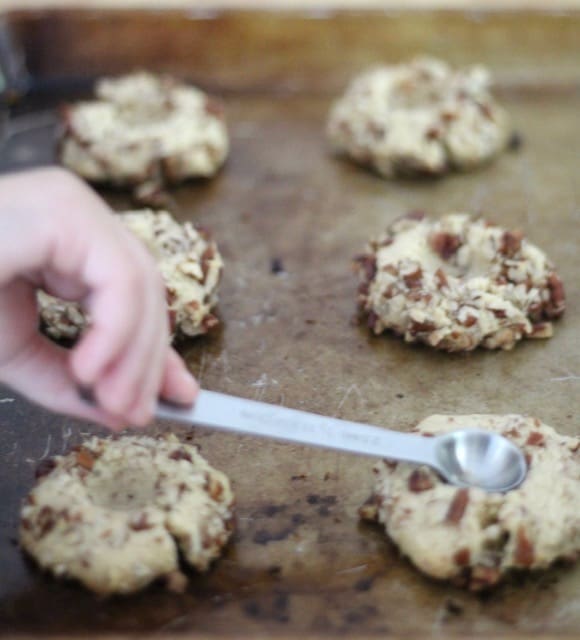 pressing thumbprint cookies down with a spoon