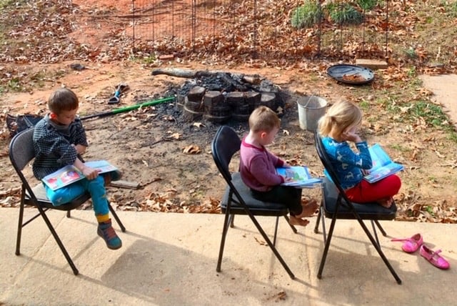 a kindergarten boy reading outside for homeschool