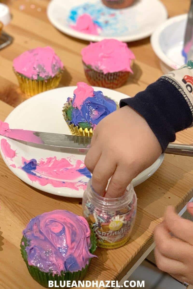 kids decorating cupcakes with pink and purple frosting for a home birthday party 