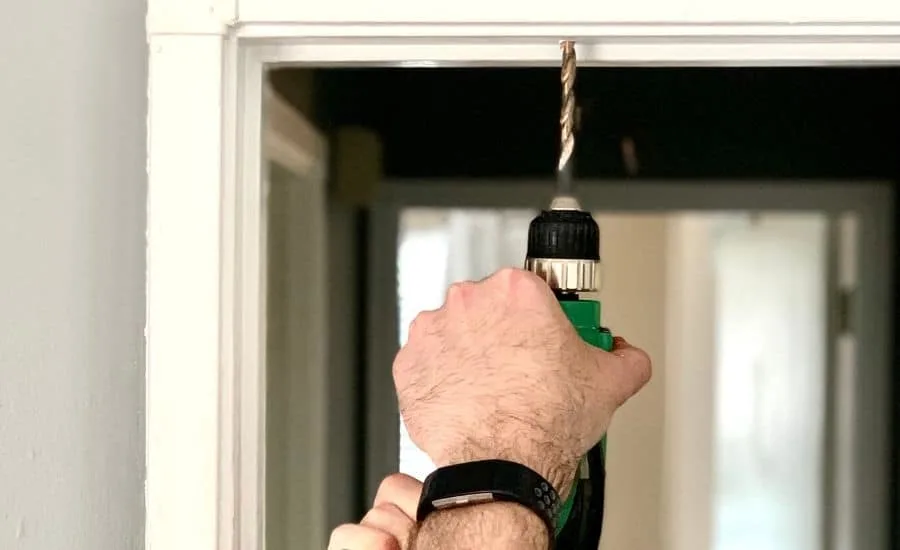 a man's hand drilling a hole for gymnastics rings to hang