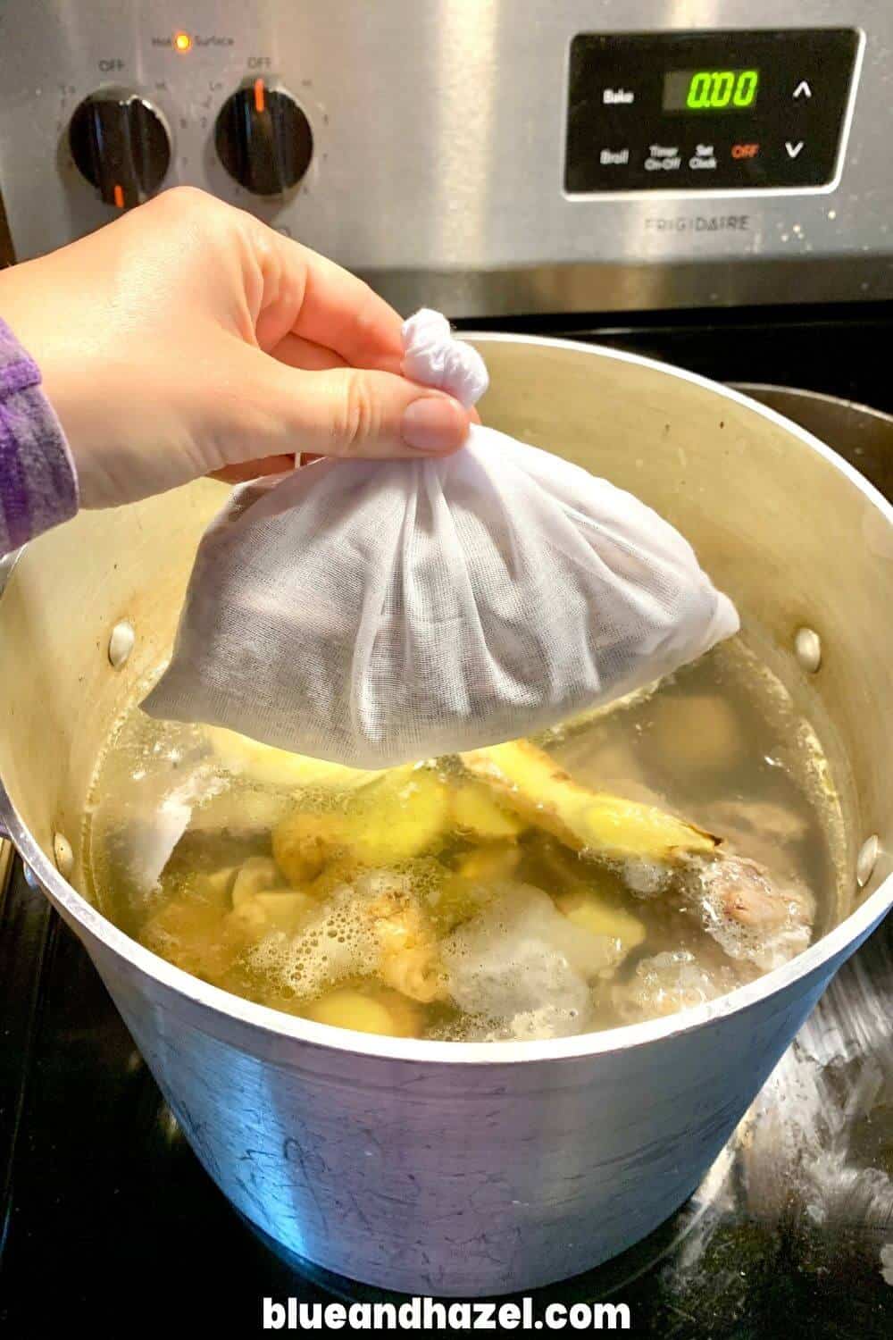 Pho spice packet inside of a muslin bag is dropped into a 12 quart stock pot full of beef bones.