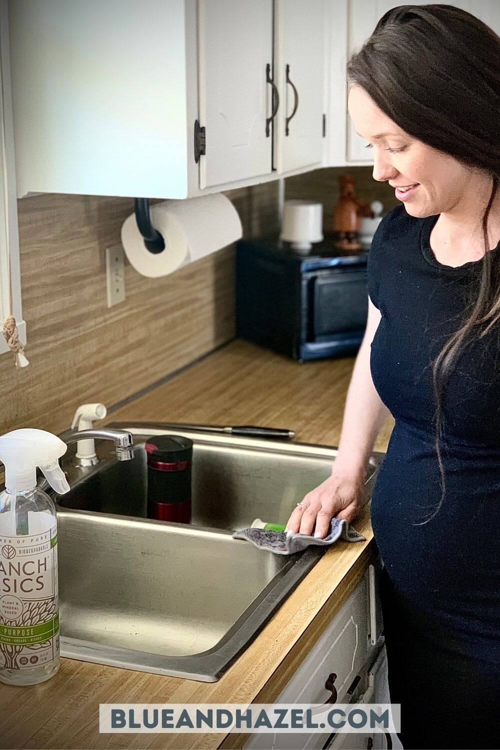 A pregnant woman cleaning a sink using Branch Basics all purpose cleaner. 