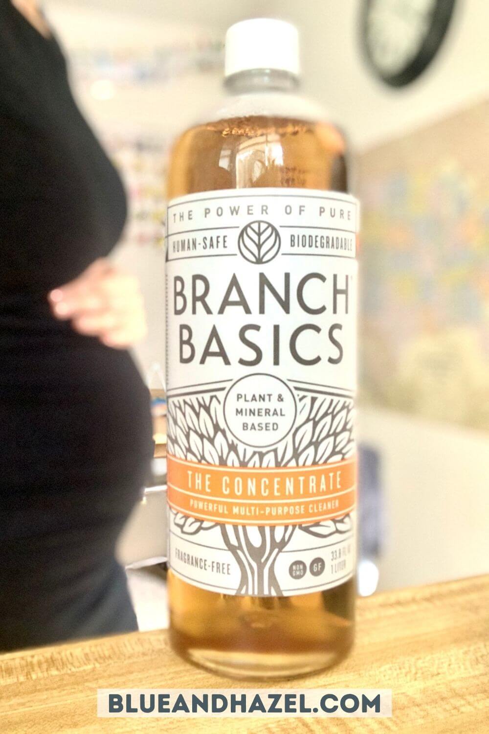 close up of branch basics bottle of concentrate with a pregnant woman standing behind. 