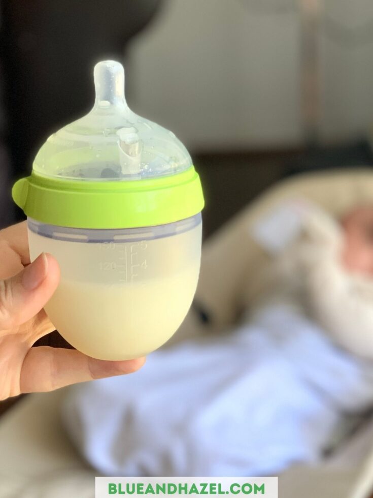 Close up of a Comotomo 5 oz silicone baby bottle with a baby blurred in the background