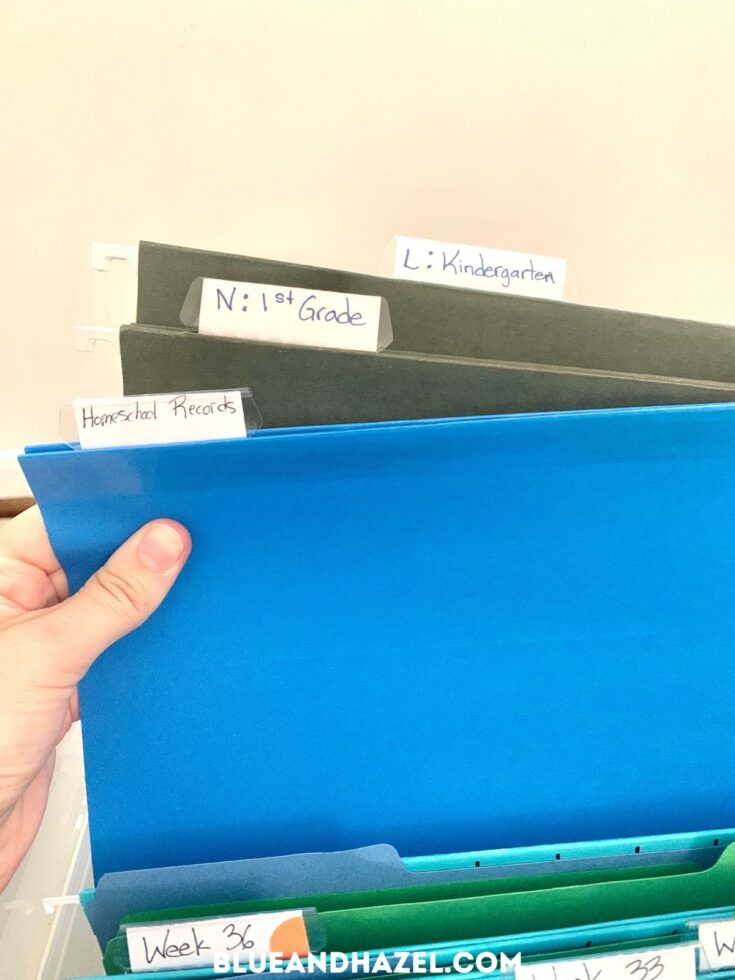 Blue file folders holding homeschool work stored in a clear homeschool crate.