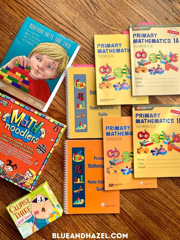 Singapore math 1A & 1B textbook, workbook, and home instructors guide next to the math games clumsy thief and math noodles. 