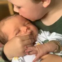 newborn baby held by his big brother