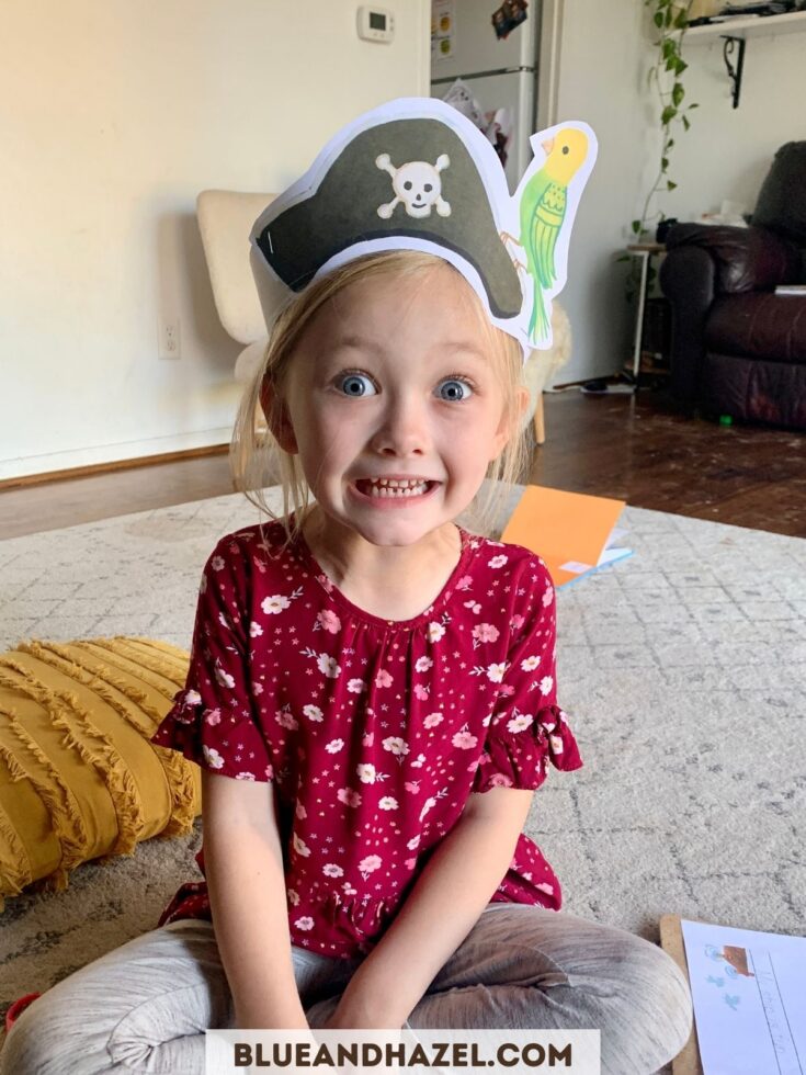 Kindergarten girl smiling wearing a pirate hat made out of paper from a Dash Into Learning activity pack. 