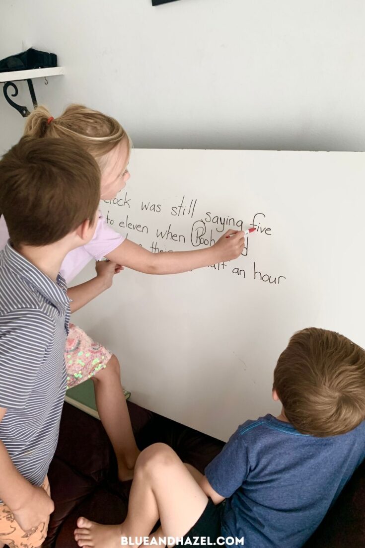 Board work for homeschool language arts. Two young kids circling words in a sentence on a whiteboard. 