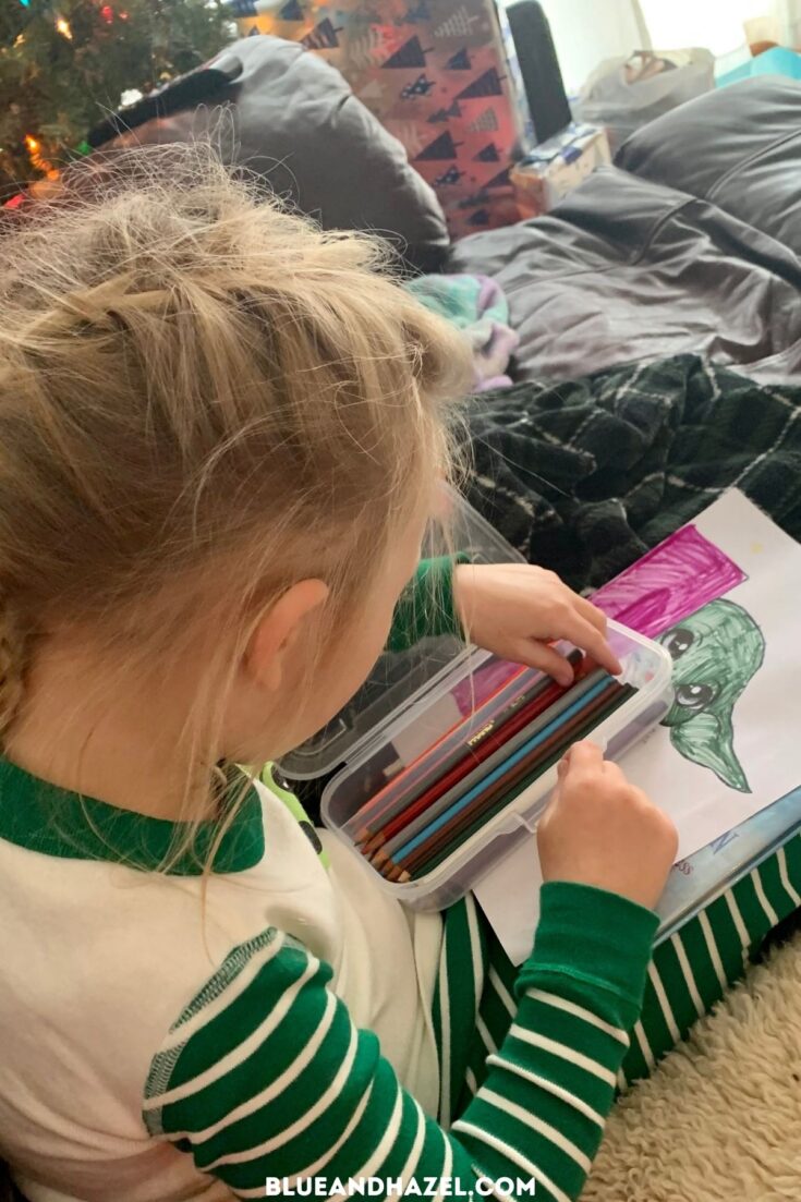 A little girl coloring baby yoda from star wars during quiet time. 