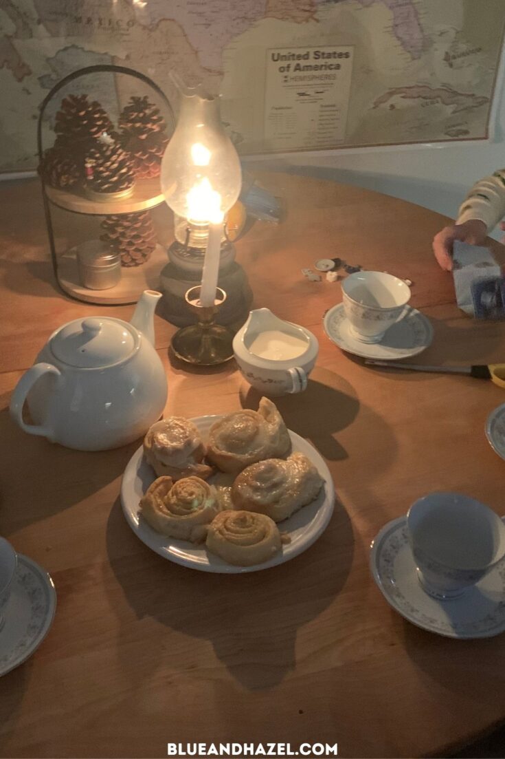 Orange rolls and teacups set on a table with a lantern for Christmas morning as a special and budget friendly Christmas tradition. 