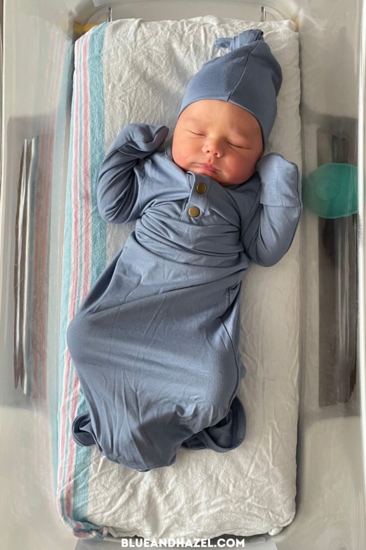 Having a 4th baby at the hospital. Here's a sleeping newborn baby boy in the hospital bed wearing a blue knotted gown and matching cap.