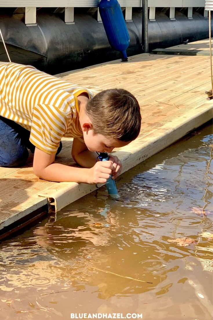 A boy using his Life Straw to get a clean drink of water out of a dirty freshwater lake.