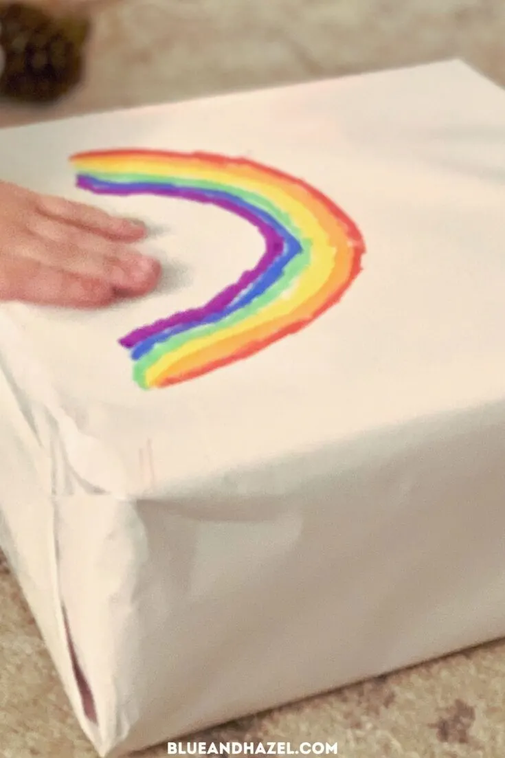 A rainbow colored onto a white wrapped christmas gift.
