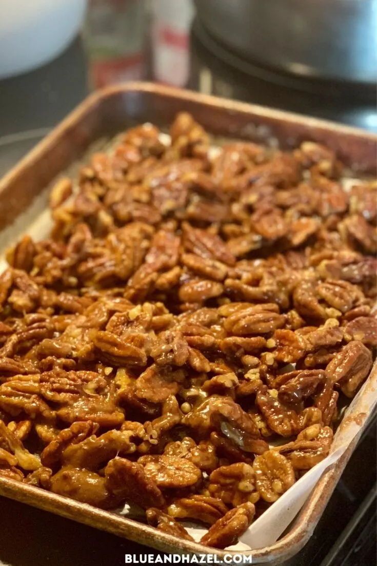 Easy candied pecans cooling on a pan lined with parchment paper.