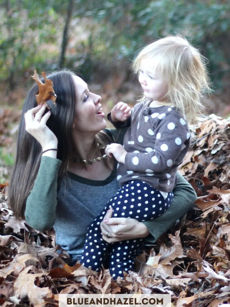 A mom and little girl playing in a pile of leaves