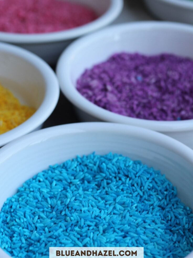 White cereal bowls filled with colorful rainbow rice used for toddler sensory bins. 