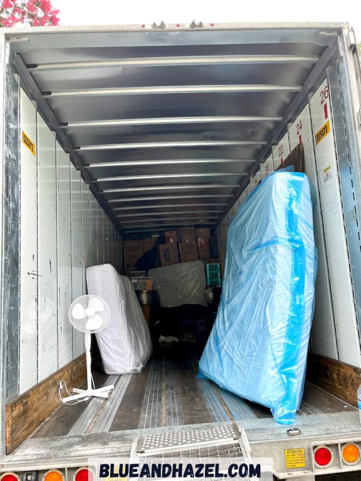 A moving truck holding boxes and two beds wrapped in plastic. 