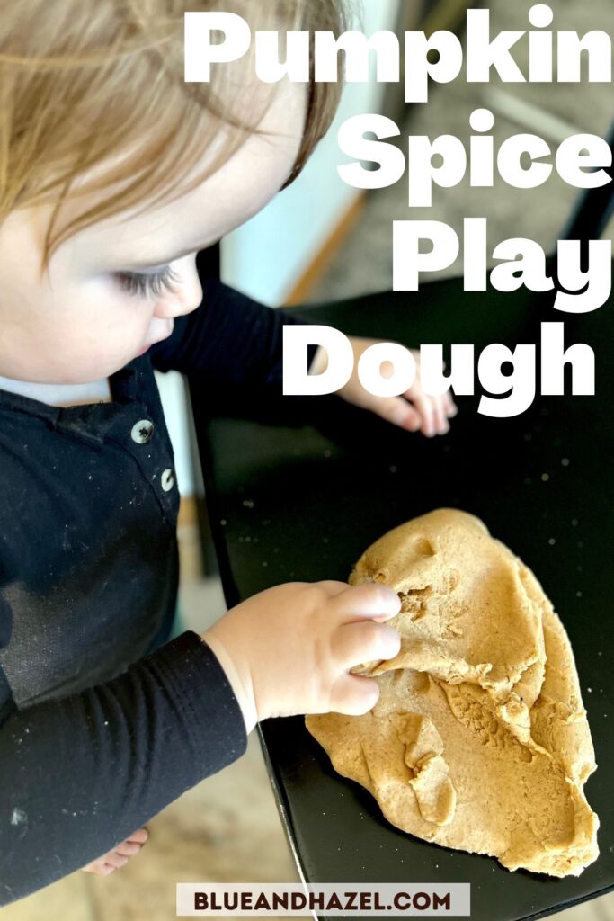 A toddler playing with pumpkin spice play dough on a black chair.