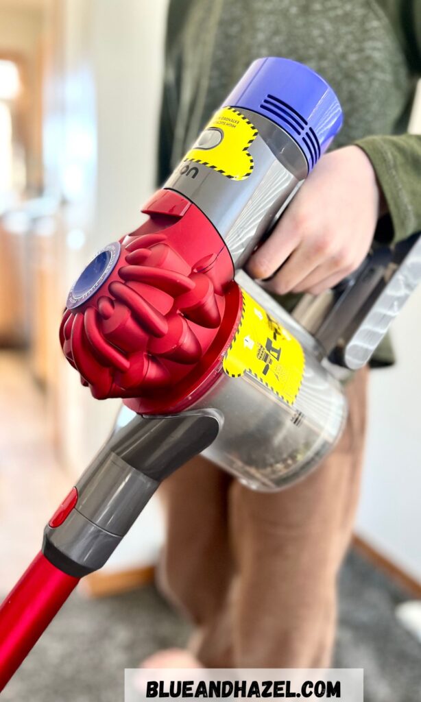 A 9 year old vacuuming using a Dyson cordless vacuum for his chore.