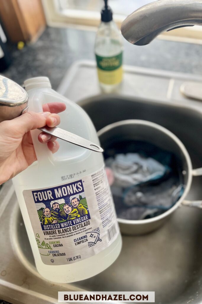 A1 gallon container of vinegar container in a kitchen sink used to clean stinky Norwex microfiber cloths.