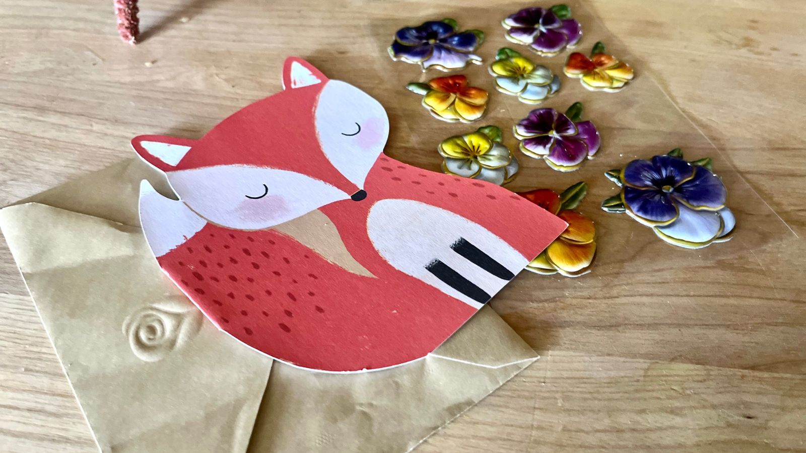 A fox stationary card next to some flat flower stickers that will go inside the envelope