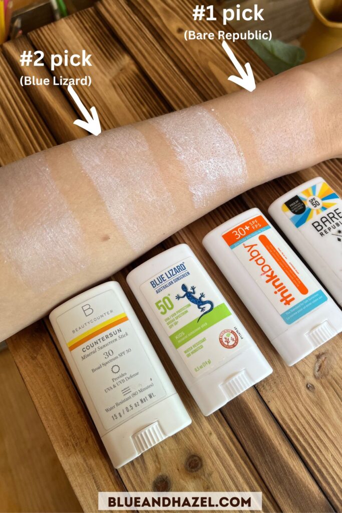 An arm with 4 samples of stick sunscreen side by side including Beauty Counter sunscreen stick, Blue Lizard Kids SPF 50 sunscreen stick, Thinkbaby SPF 30 sunscreen stick, and Bare Republic SPF 50. 